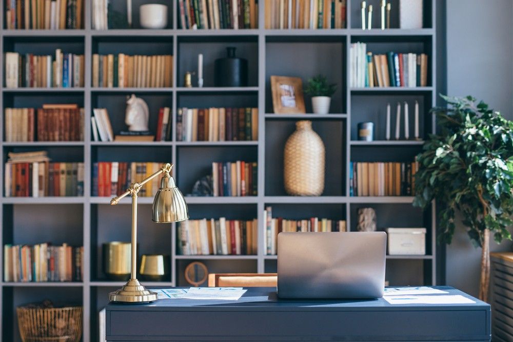 Table with laptop in home office interior.