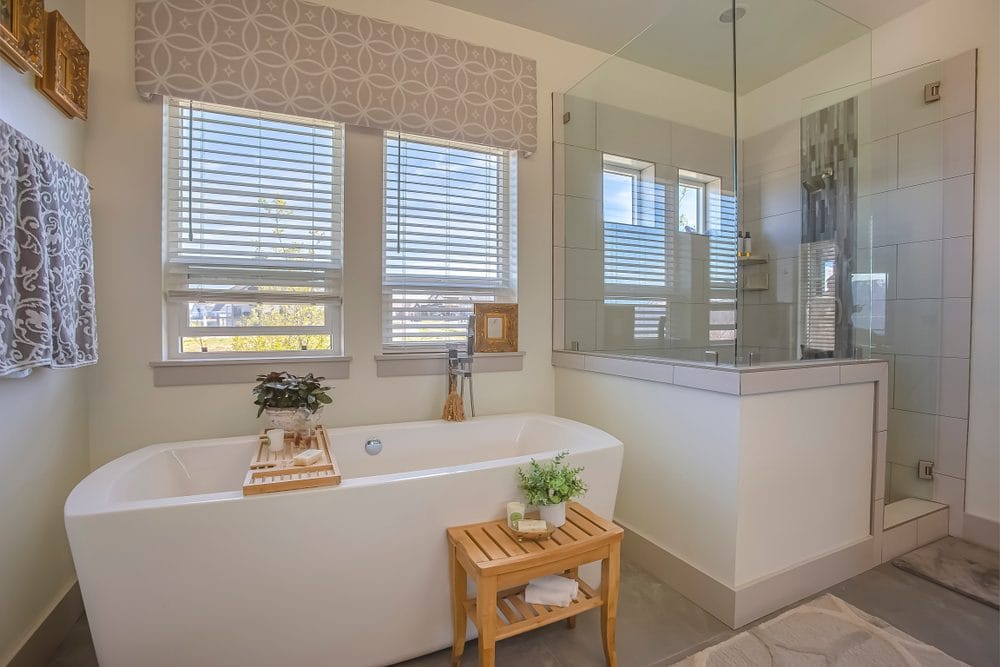 Bathtub and shower stall in front of windows with valance and blinds