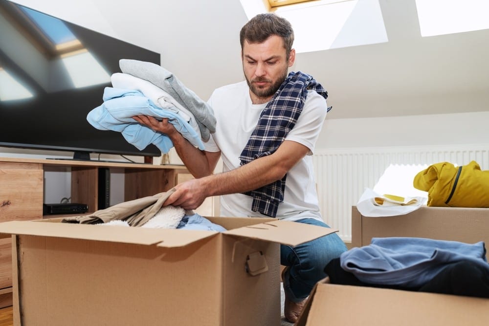 Man sorting clothes into boxes