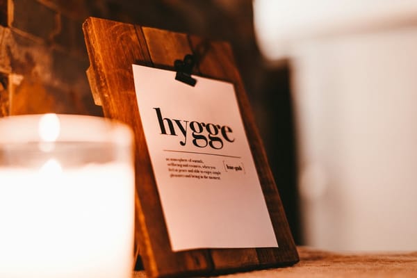 signe hygge sur des planches en bois à côté d'une bougie