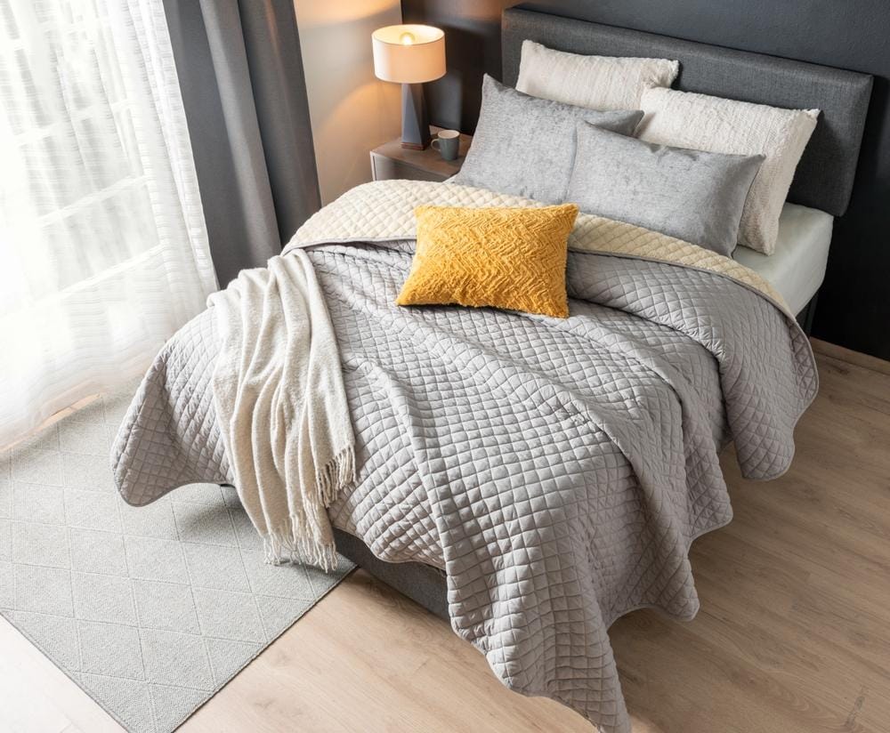 bed with a set of pillows, a grey blanket and a cotton throw, fabric headboard