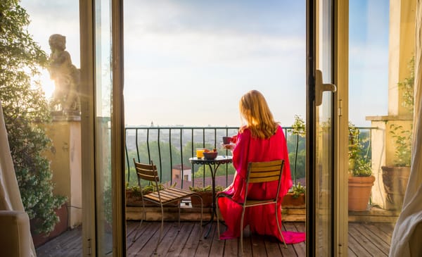 una donna che beve un caffè su un balcone a Roma