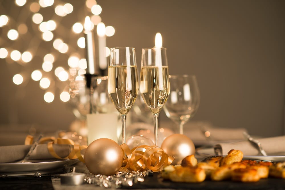 new years eve party table with champagne flute ribbon and golden glitter