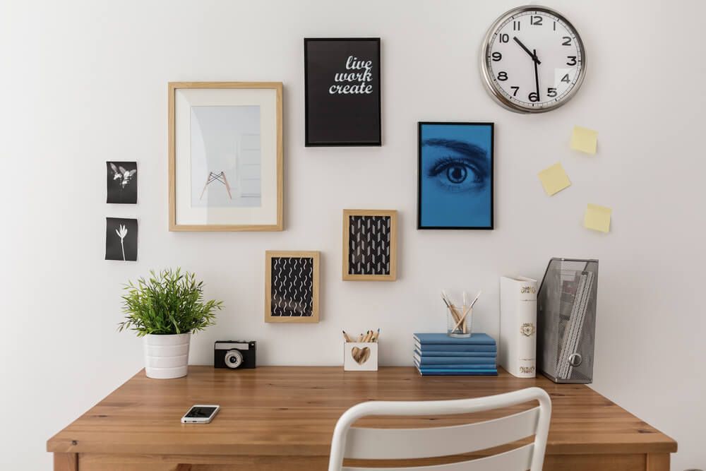 wooden desk with a chair against a wall with frames